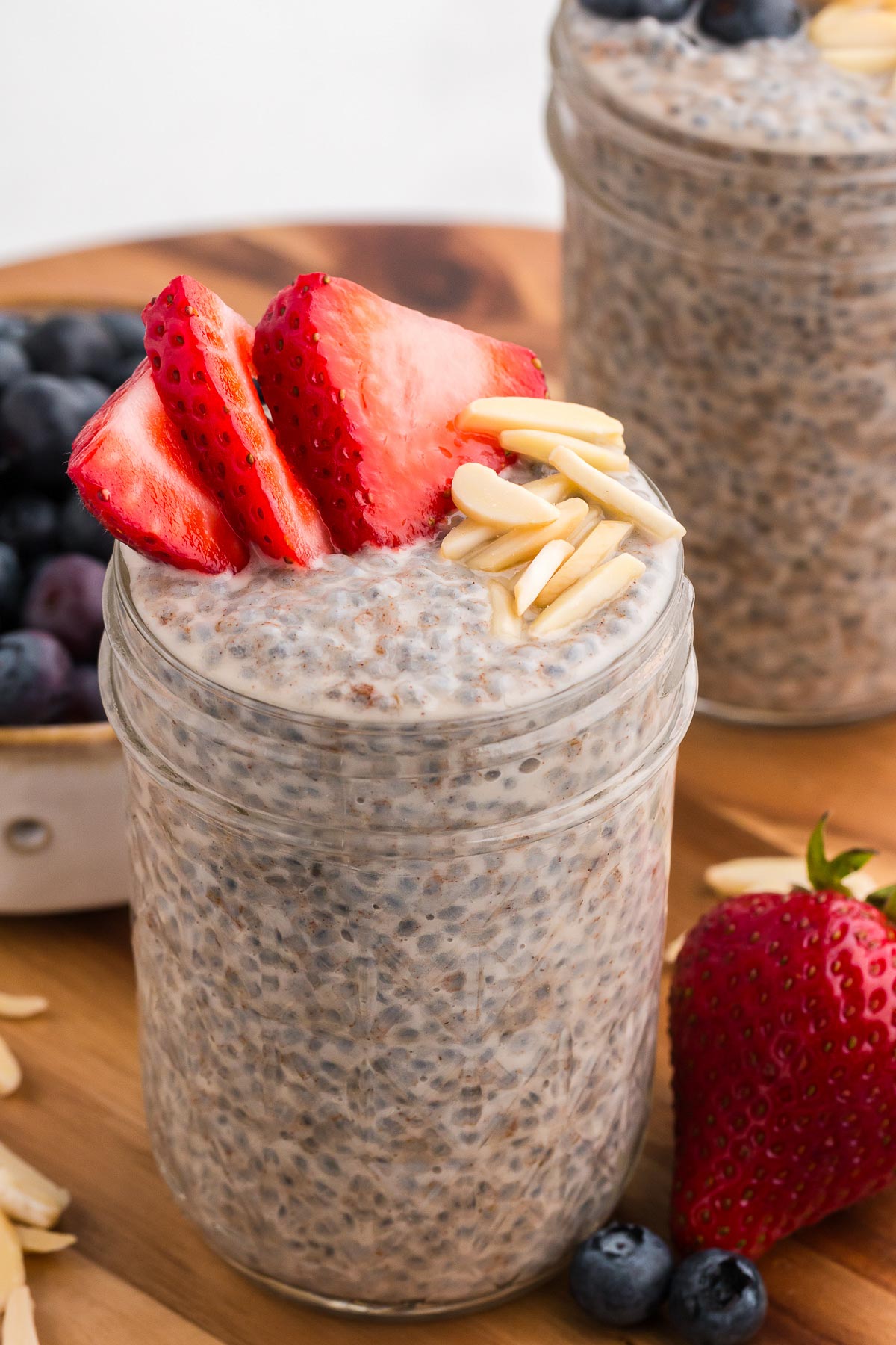 A jar full of basil seed pudding with strawberries and slivered almonds