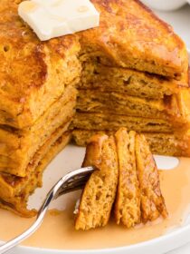 Stack of pumpkin pancakes with a section cut out and several pieces on a fork.