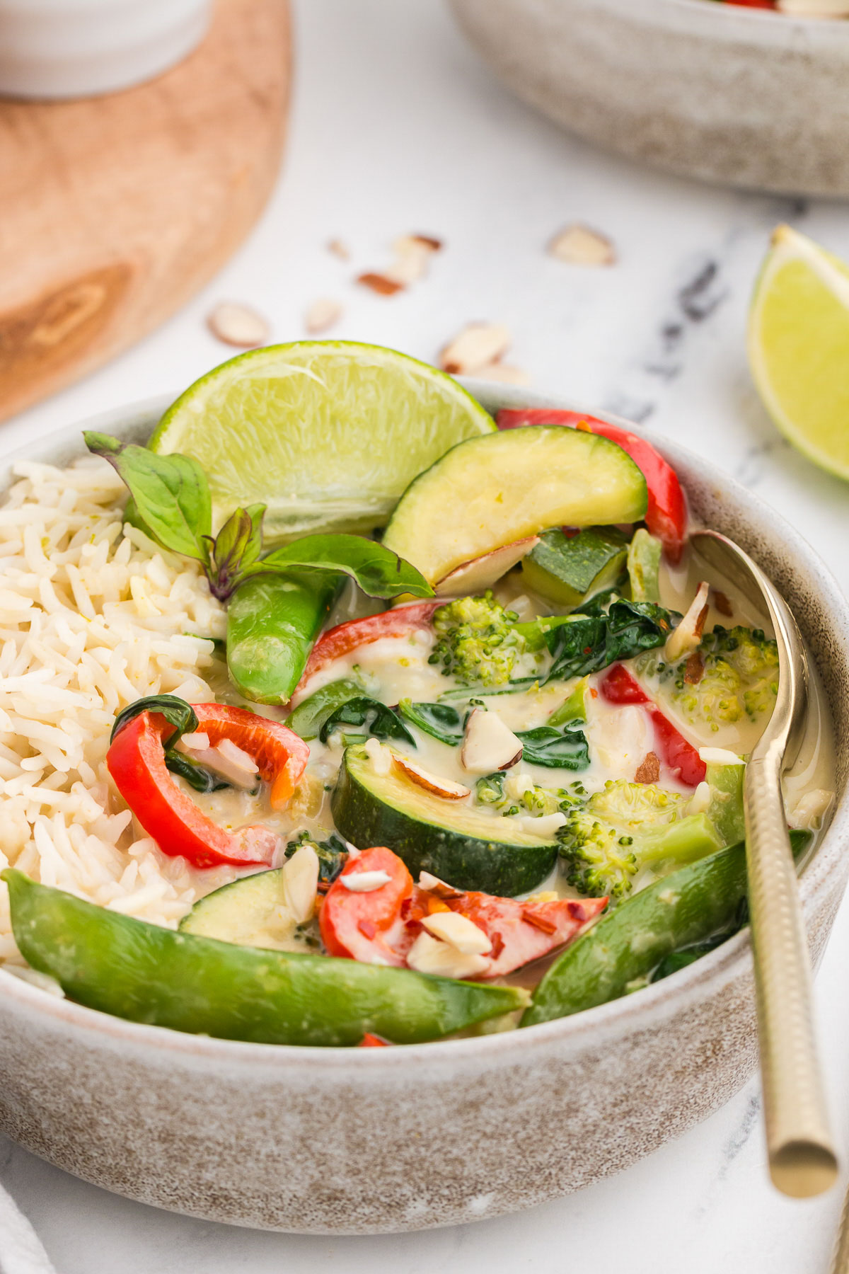 A rustic bowl full of Thai Green Curry Vegetables and brown rice.
